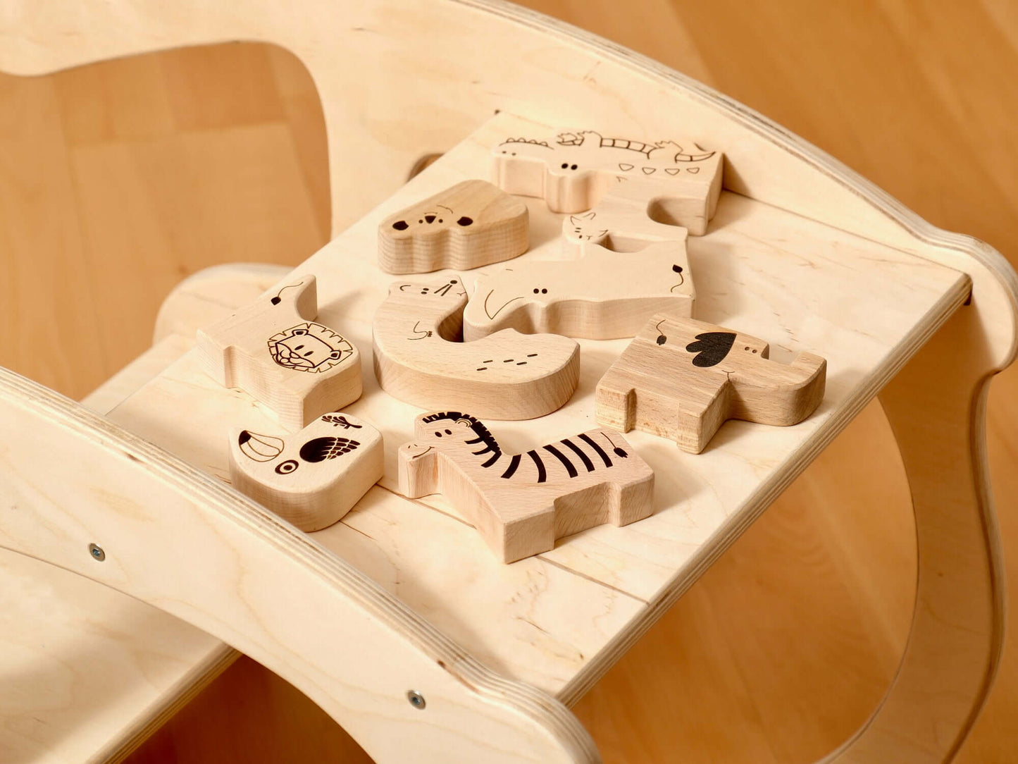 Colorful wooden safari animal puzzle pieces on a Montessori climbing set for toddlers, promoting hands-on learning.