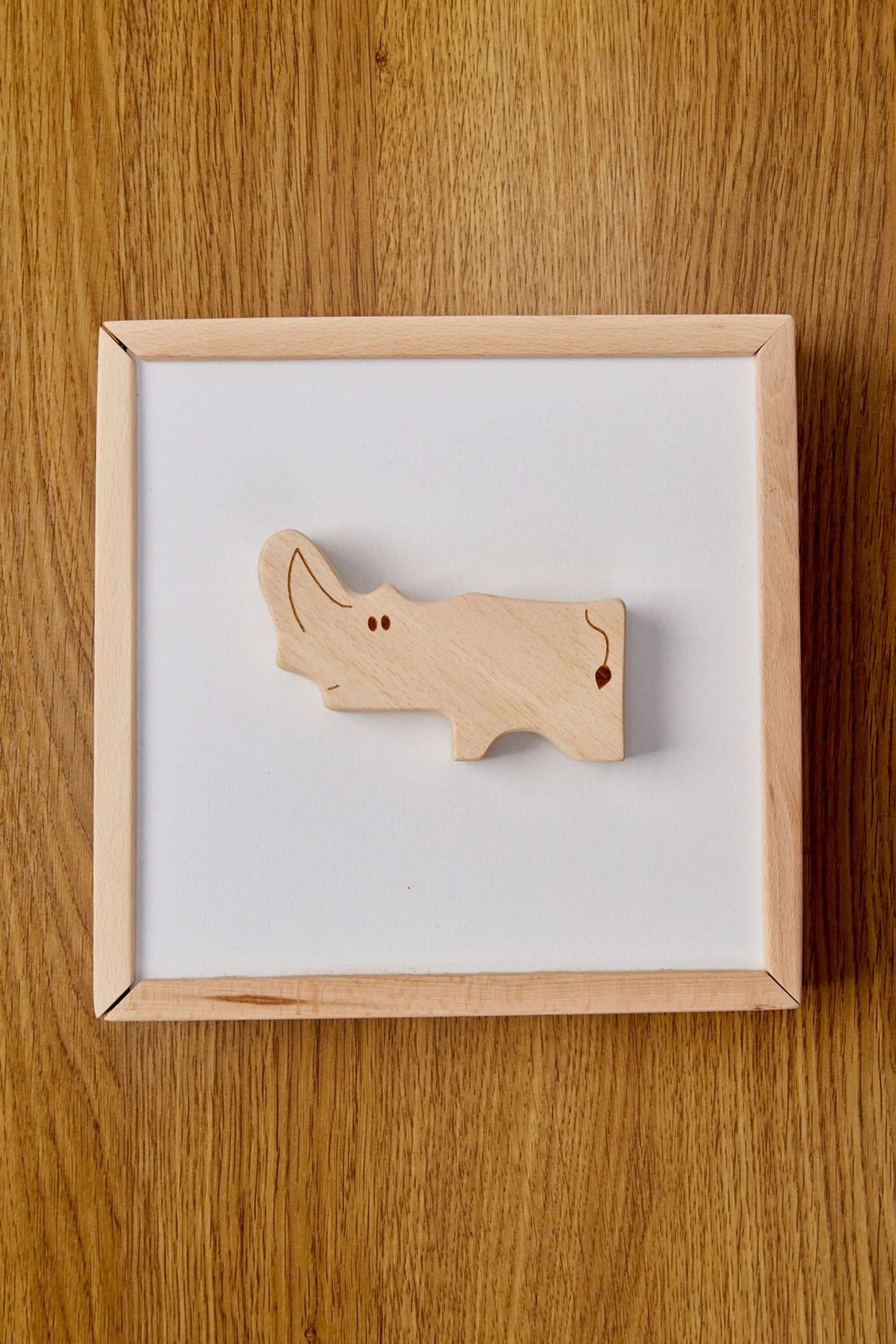 Wooden rhino puzzle piece on a white board, part of eco-friendly toddler learning toy.