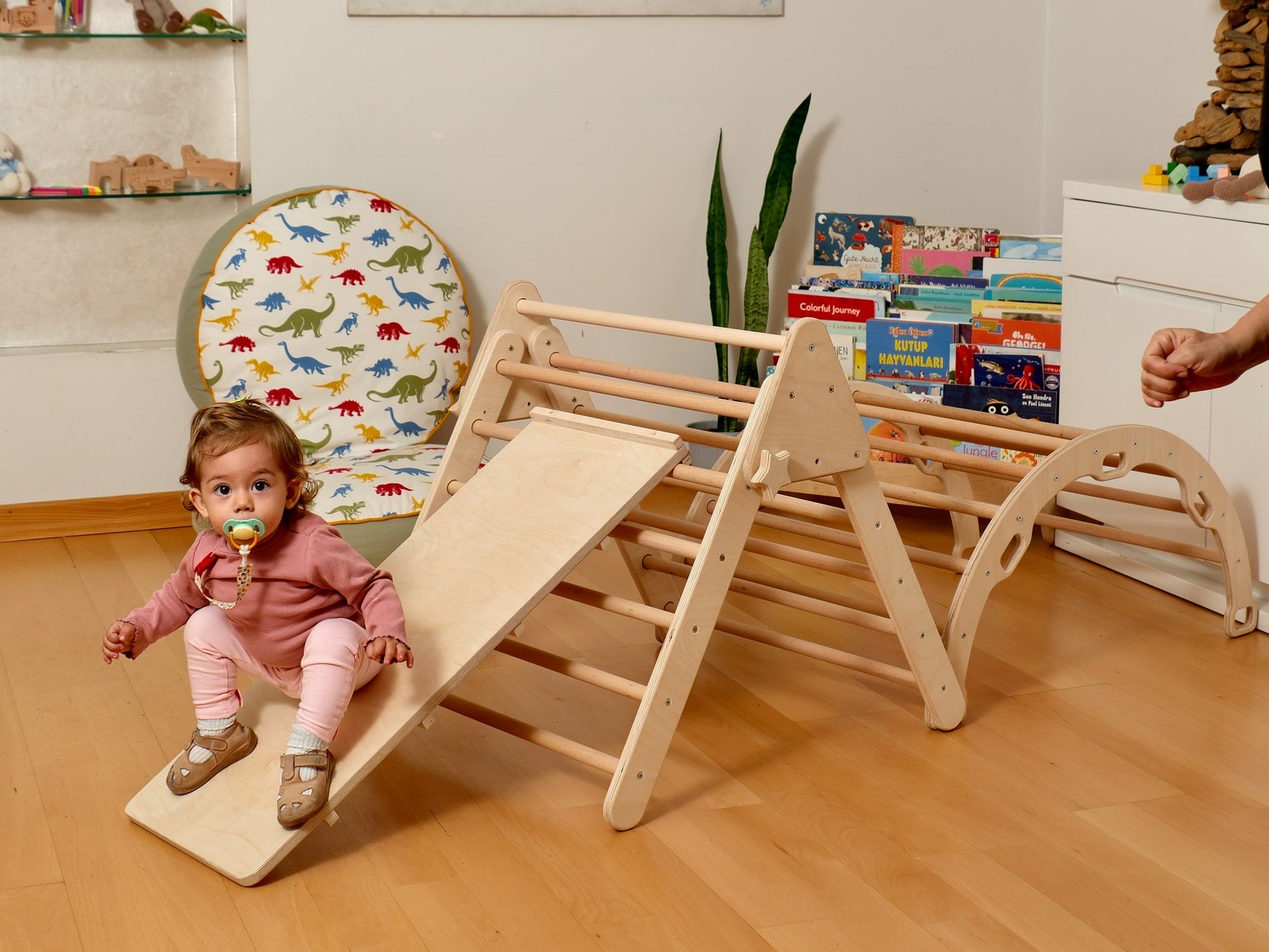 Toddler enjoying a Montessori indoor playground with climbing arch and slide, perfect for play and learning.