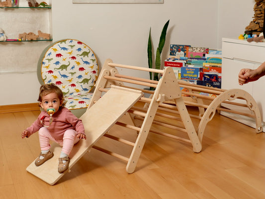 Toddler enjoying a Montessori indoor playground with climbing arch and slide, perfect for play and learning.